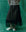 A person showcases women's clothing by pairing a striped top with The Era Skirt in black, designed by THE GREAT. HOL 24, and high-top sneakers, all set against a green background.