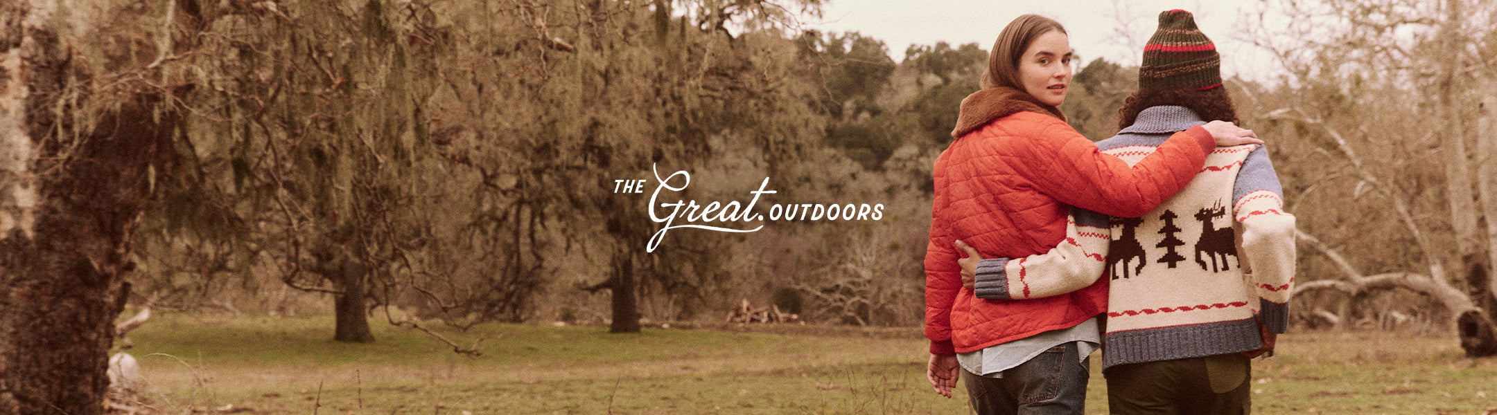 Two people in winter clothing walk arm-in-arm through a wooded area with the text "The Great Outdoors" on the image.