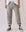 A person standing against a plain backdrop wears The Cropped Sweatpant. Solid by THE GREAT. CORE KNITS in Varsity Grey, featuring ribbed cuffs and a drawstring waistband. They complete the look with a white top and black high-top sneakers. The person's face is not visible.